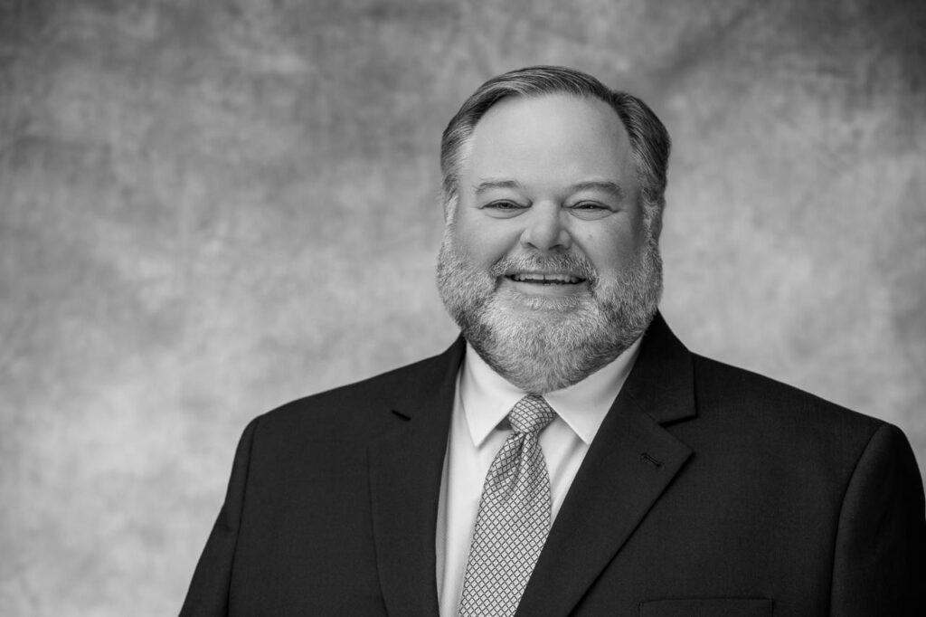 Smiling man in a suit, grayscale portrait.