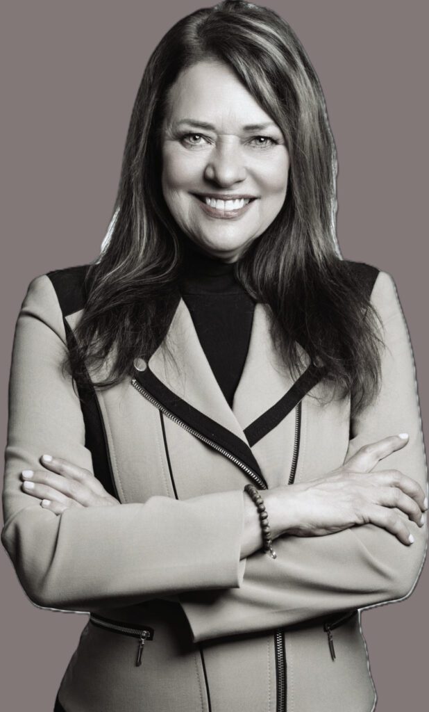 Smiling woman in a jacket, arms crossed.