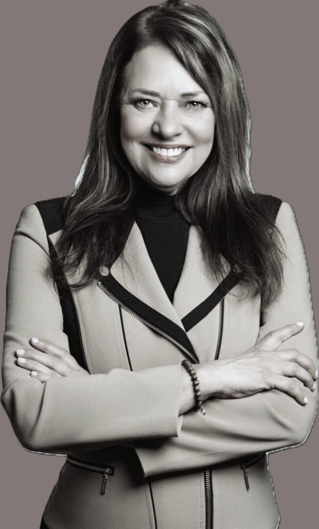 Smiling woman in a jacket, arms crossed.